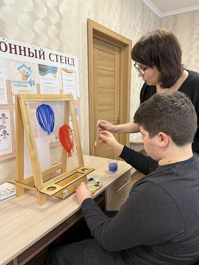 Мальчик нарисовал на прозрачном мольберте два воздушных шара