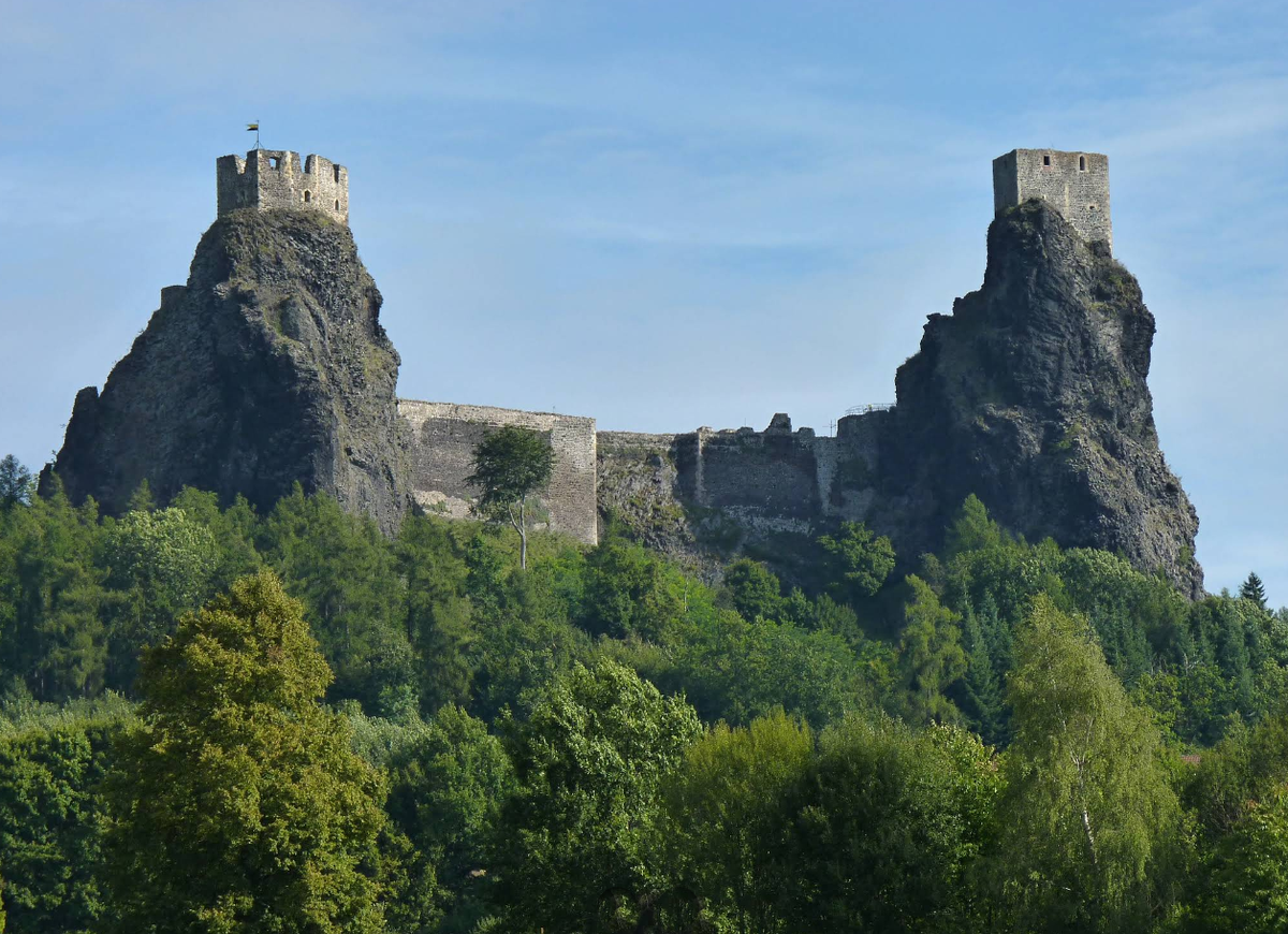 Панорамный вид на замок Троски (Trosky Castle) в Чехии, башни Баба и Дева на базальтовых скалах, пейзаж Чешского Рая с зелеными лесами и холмами.

