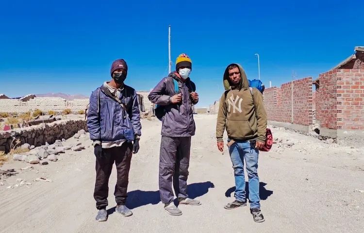 Трое венесуэльских мигрантов ждут возможности пересечь границу с Чили, надеясь избежать встречи с полицией и сделать это ночью, в Писиге, Боливия, 25 октября 2021 года. 