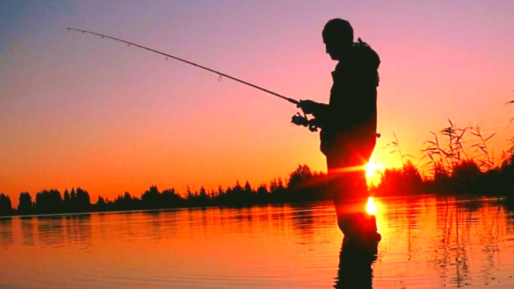 Рыболов со спиннингом на заре