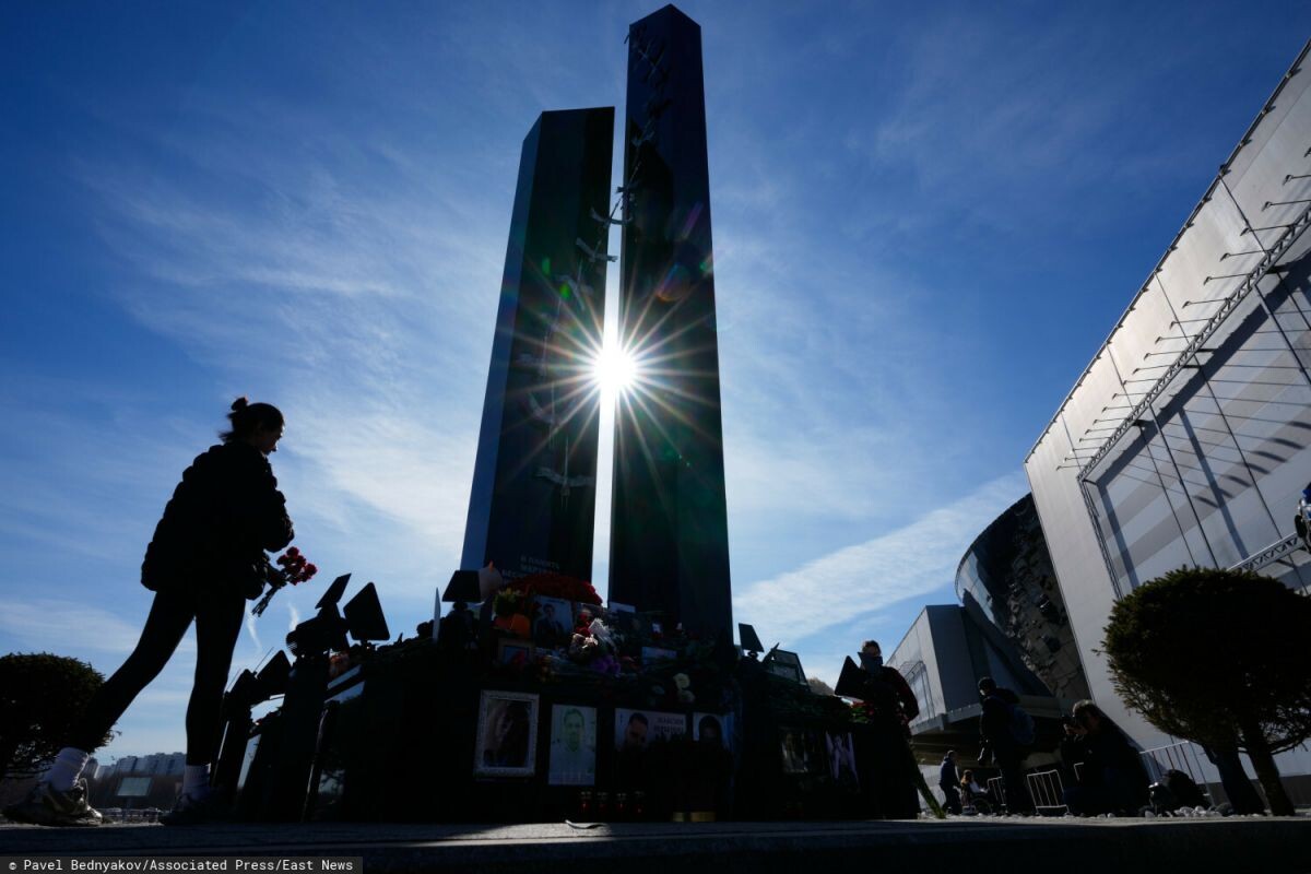 Женщина возлагает цветы к мемориалу у концертного зала «Крокус-Сити», 22 марта 2026 года.