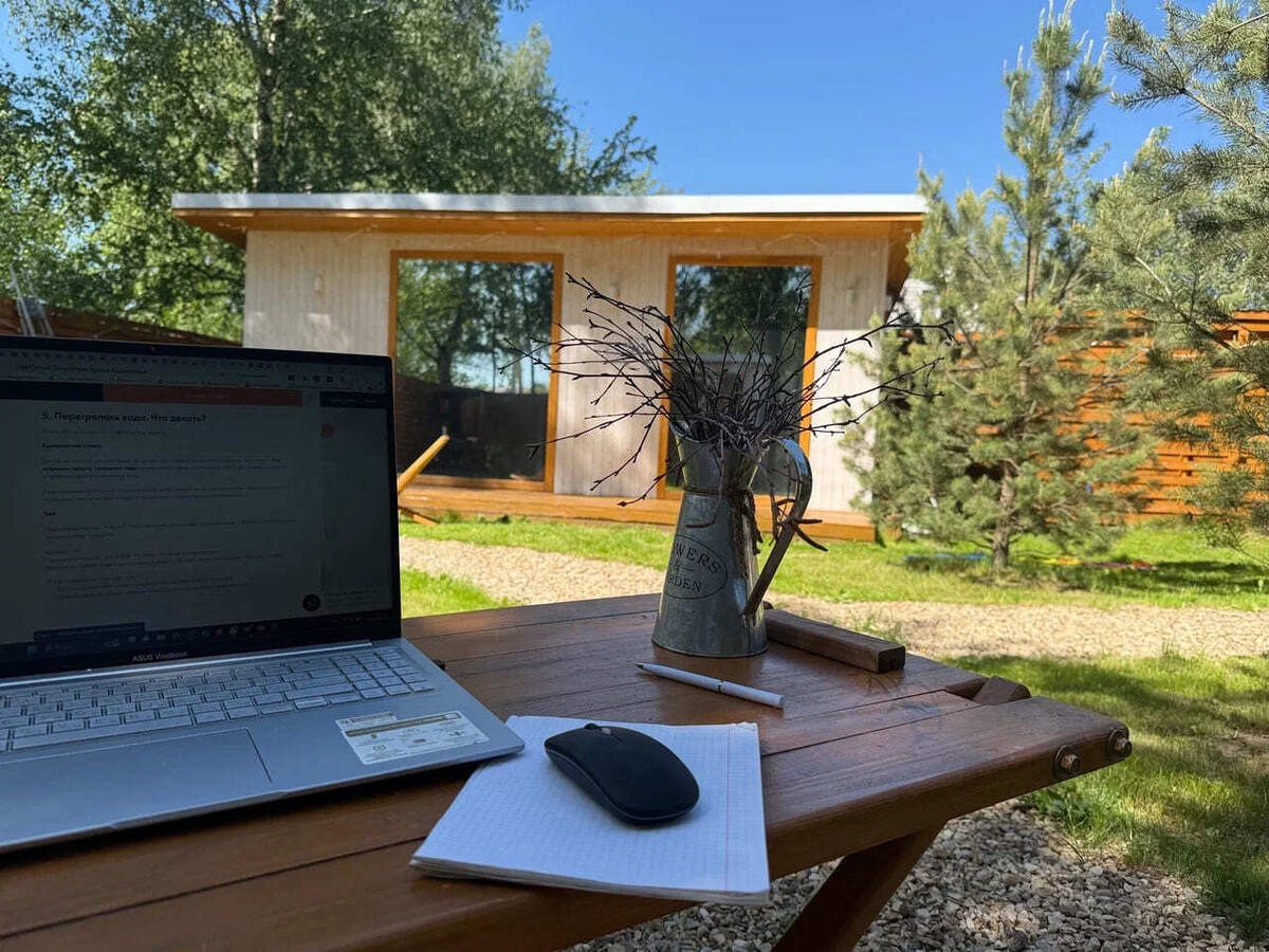 Ноутбук на столе у домика — удалённая работа за городом в будни