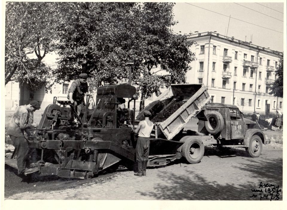     Комплексная механизация работ по устройству асфальтовых дорог. Разгрузка с самосвала асфальтобетона в асфальтоукладчик. Трест "Стройгаз" г. Барнаул. 1955 г.. Источник: goskatalog.ru, архив АГКМ, Каманин С.И.