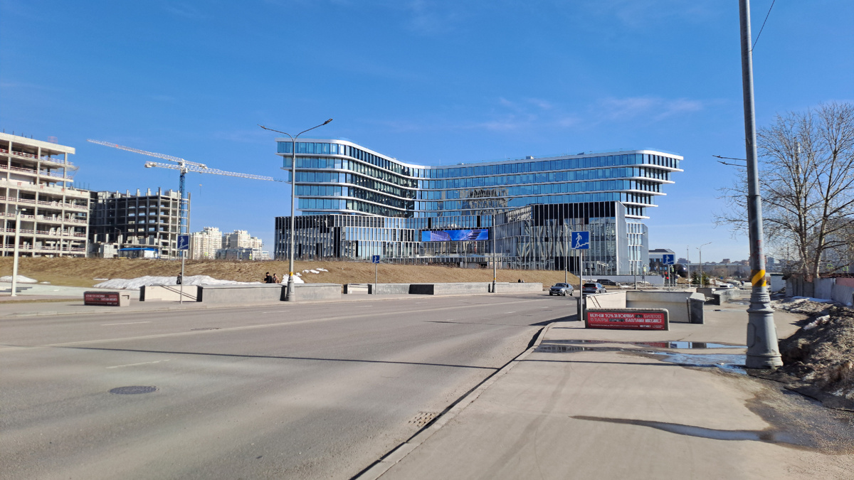 Справа от меня вот такое здание современное. Не знаю, что там находится. А я напротив того ☝️здания, на остановке стою.