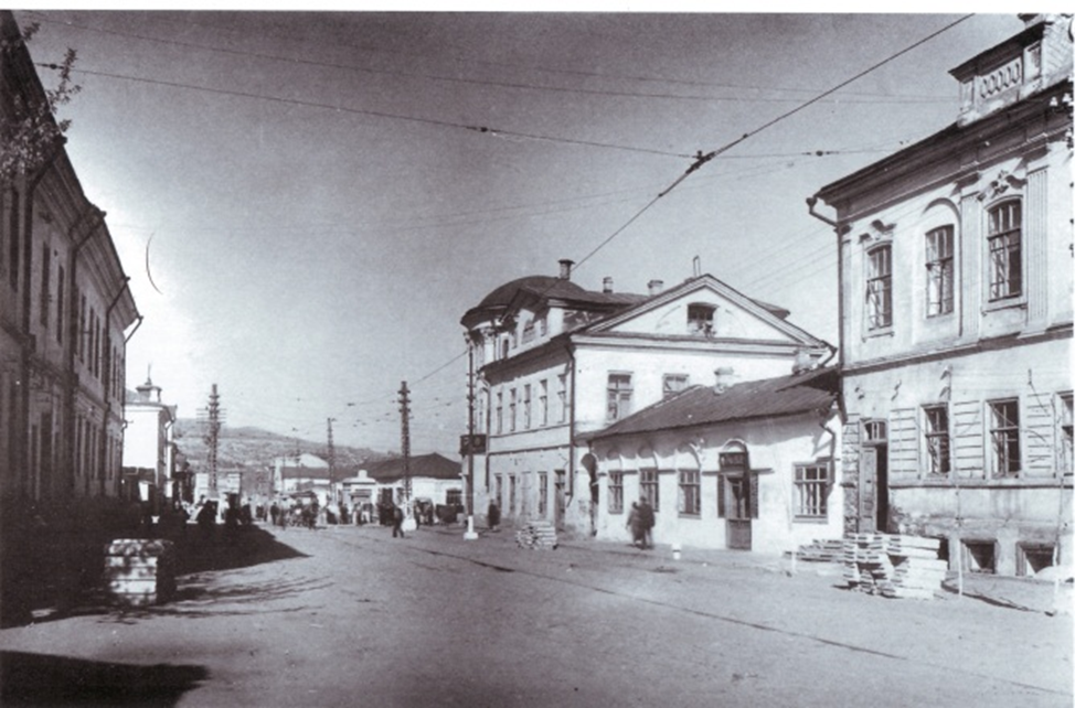 Справа, ближе к зрителю- дом Полеводина. Дальше -1-этажные лавки Жижина и  дом Жижина (бывшие Никитина), в первом этаже дома  также лавки (магазины).