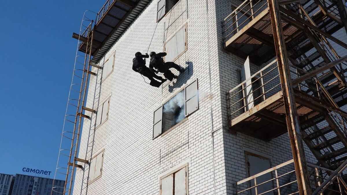   Сотрудники-высотники по команде командира с земли спускаются на нужный этаж, стреляют шумовыми патронами и проникают внутрь помещения / newizv.ru