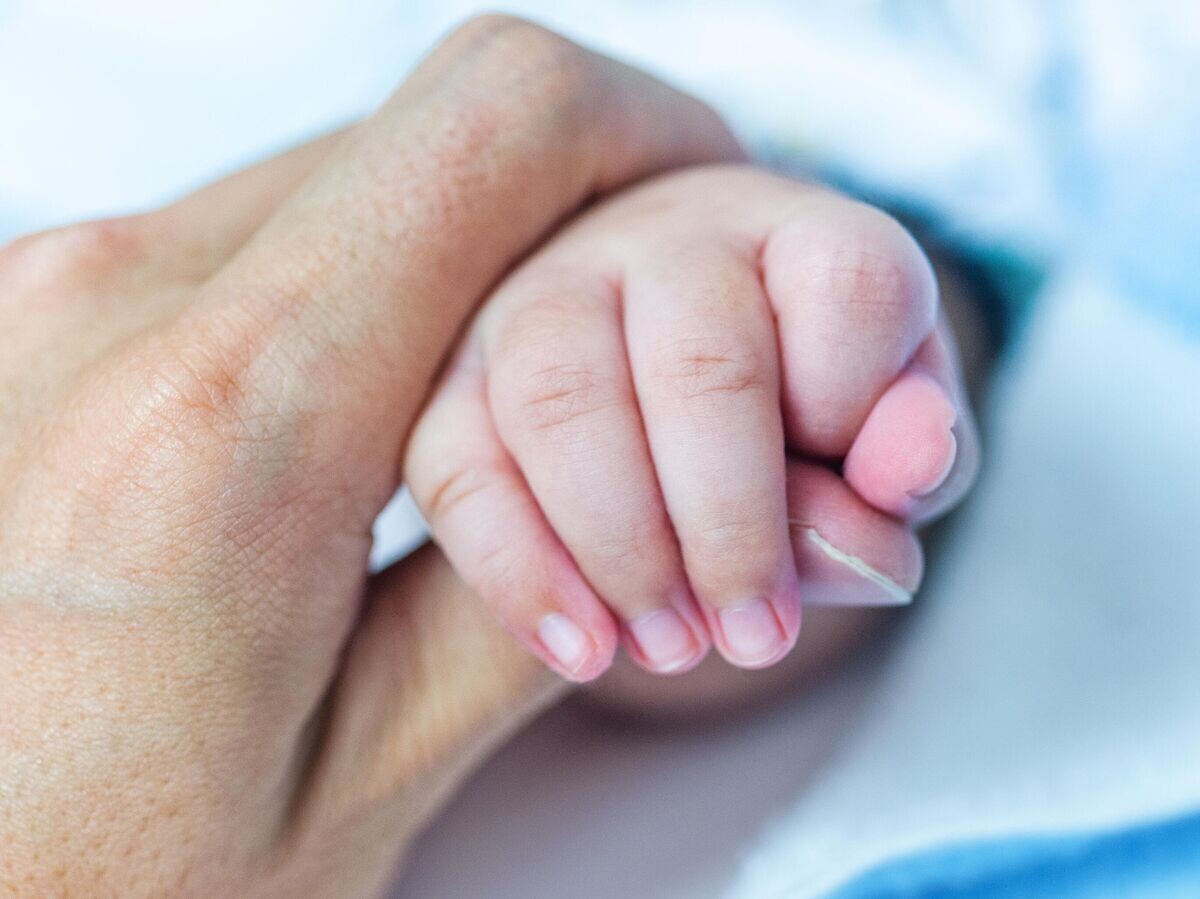    Женщина держит новорожденного за ручку | © iStock.com / hxdbzxy