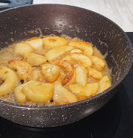 Дольки груши в янтарной карамели на сковороде, масло и мед пузырятся вокруг.
