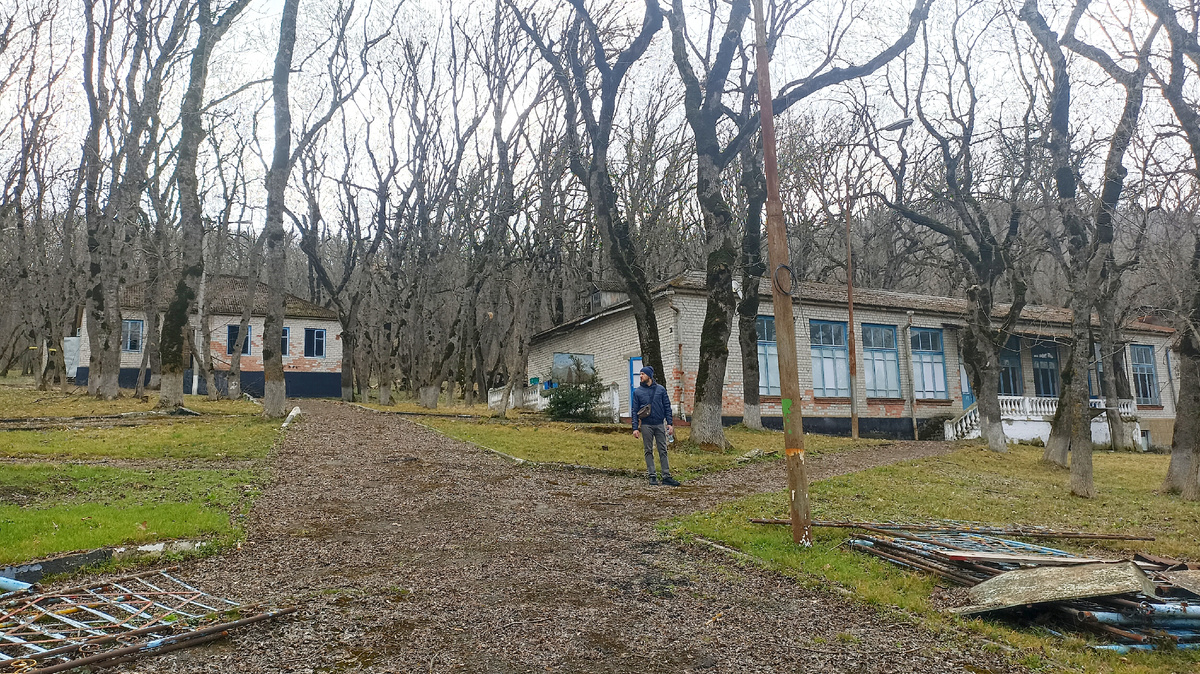 Справа бывшее здание столовой, ржавый фонарь, широкая дорожка, ведущая от проходной к столовой и возможно медпункту (левее здание) 