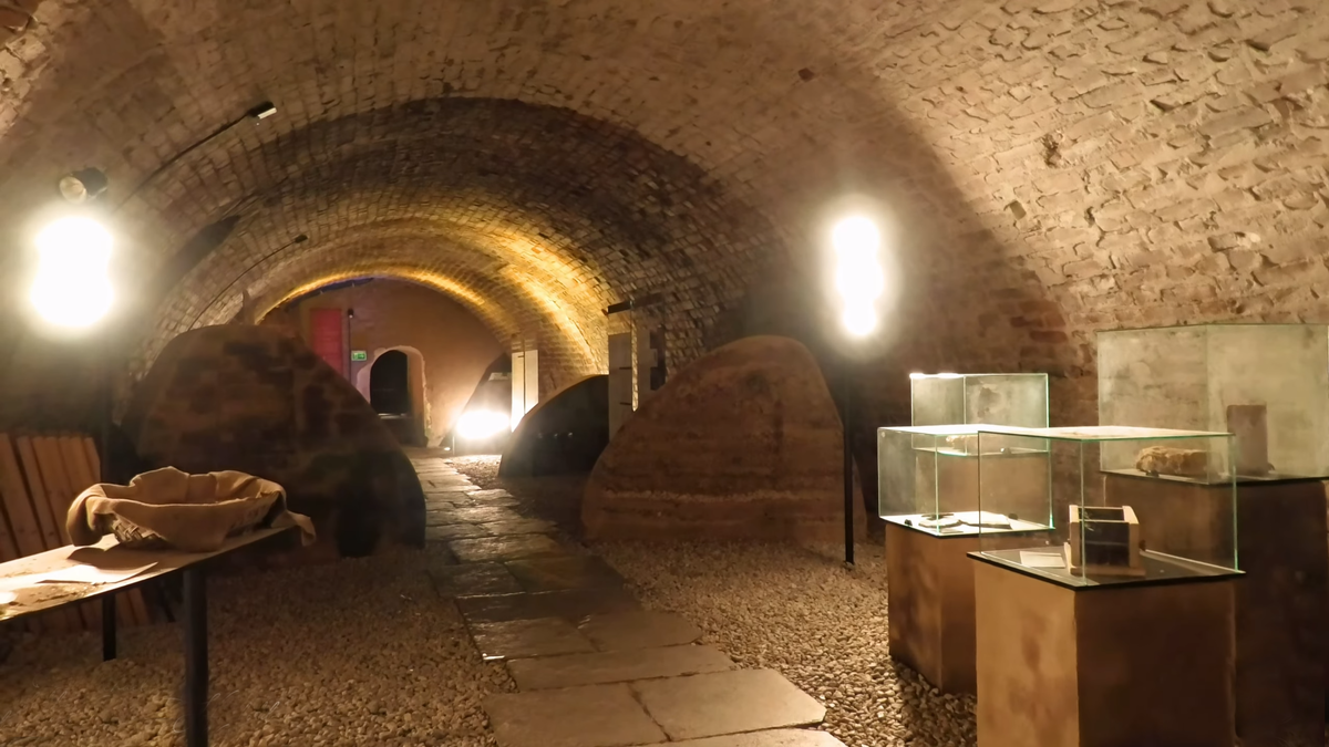 «Тайны замковых подземелий: там, где скала оживает».
Спускаясь в эти сводчатые залы, вы буквально заходите внутрь 50-метровой скалы, на которой стоит Рохсбург. Здесь, в прохладе каменных арок, время течет иначе. Обратите внимание на витрины: в них хранятся археологические находки, обнаруженные прямо здесь, в подвалах крепости. От старинной утвари до фрагментов кладки XII века — это место позволяет увидеть фундамент истории замка в самом прямом смысле. Идеальное завершение прогулки для тех, кто хочет заглянуть за кулисы парадных залов и почувствовать настоящую мощь древней цитадели.
