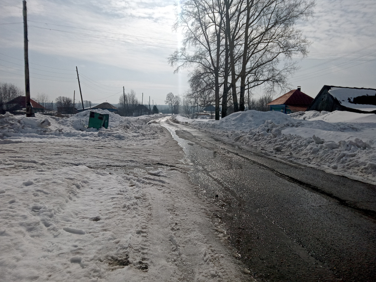 Центральная улица села, на ней есть асфальт и снежная каша вокруг