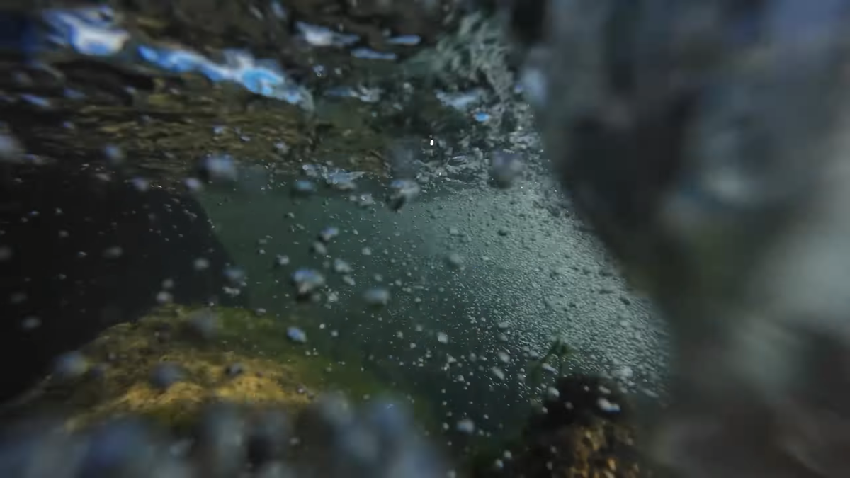 Прозрачная ледяная вода горного ручья на Алтае, брызги и подводные камни