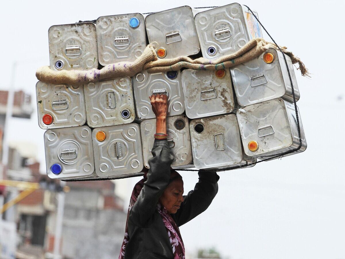    Женщина несет на голове пустые канистры из-под моторного масла в Ахмадабаде, Индия | © AP Photo / Ajit Solanki