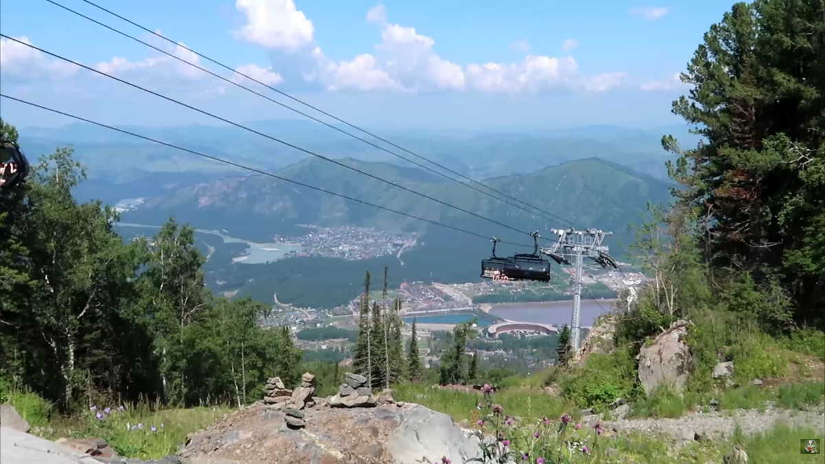 Вид, от которого захватывает дух: современные кабины канатной дороги «плывут» над склонами Малой Синюхи. Внизу — долина реки Катунь и бескрайние алтайские хребты.