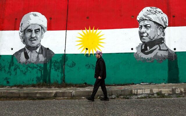 Курд проходит мимо фрески с изображением покойного лидера Освободительного движения Курдистана Мустафы Барзана (слева) и курдского политического лидера Масуда Барзани во время празднования весеннего Нового года Навруз в городе Акре, к северу от Эрбиля, в северном автономном курдском регионе Ирака, 20 марта 2026 года. (Сафин ХАМИД / AFP)