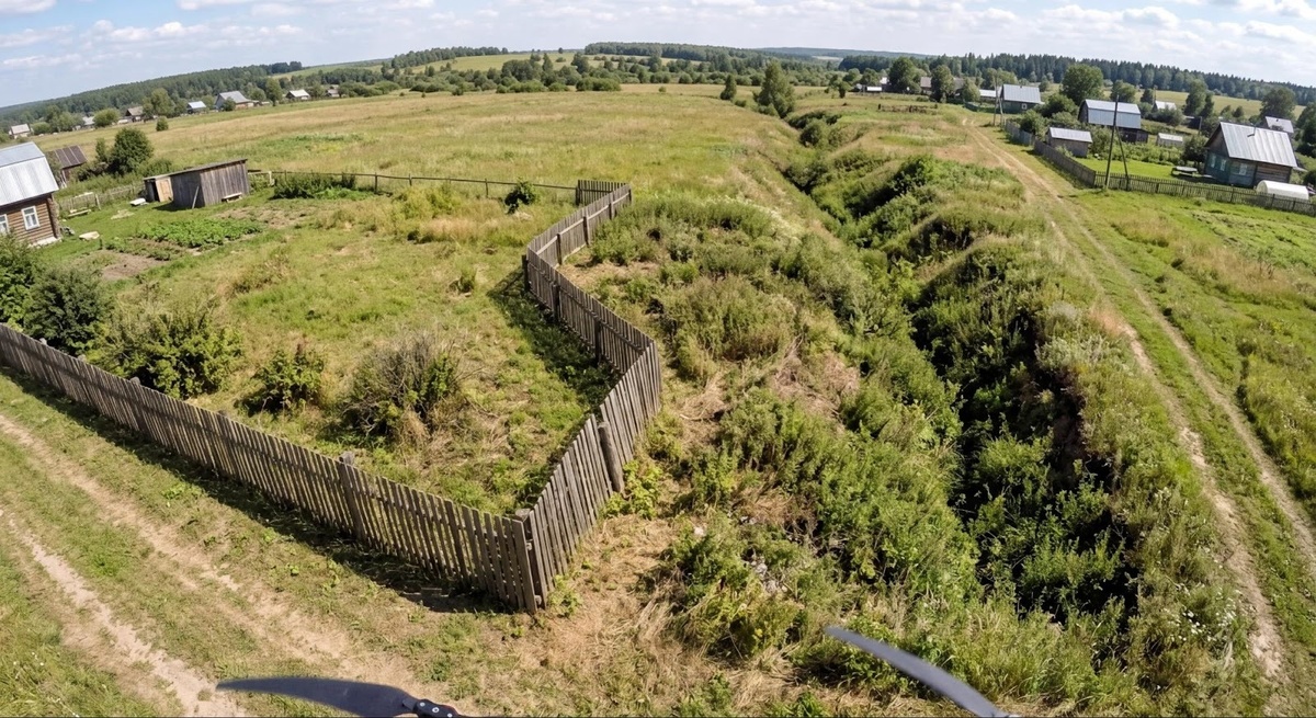 Дрон фиксирует нарушение: забор, сдвинутый на чужую территорию, с заросшим оврагом на фоне