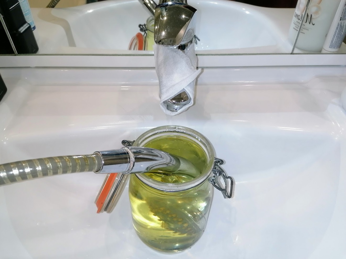 Чищу от налёта душевую лейку. Вода окрасилась жёлтым: это лимонная кислота заработала. Фото автора