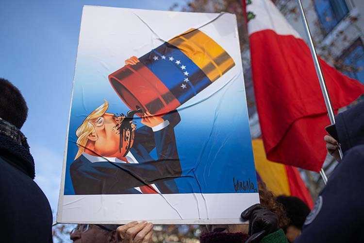    Дональд Трамп сравнил этот шаг с операцией США в Венесуэле, нефтяная отрасль которой сейчас находится под контролем Штатов (на фото: карикатура на Трампа, пьющего венесуэльскую нефть).   
Фото: © David Canales / Keystone Press Agency / www.globallookpress.com