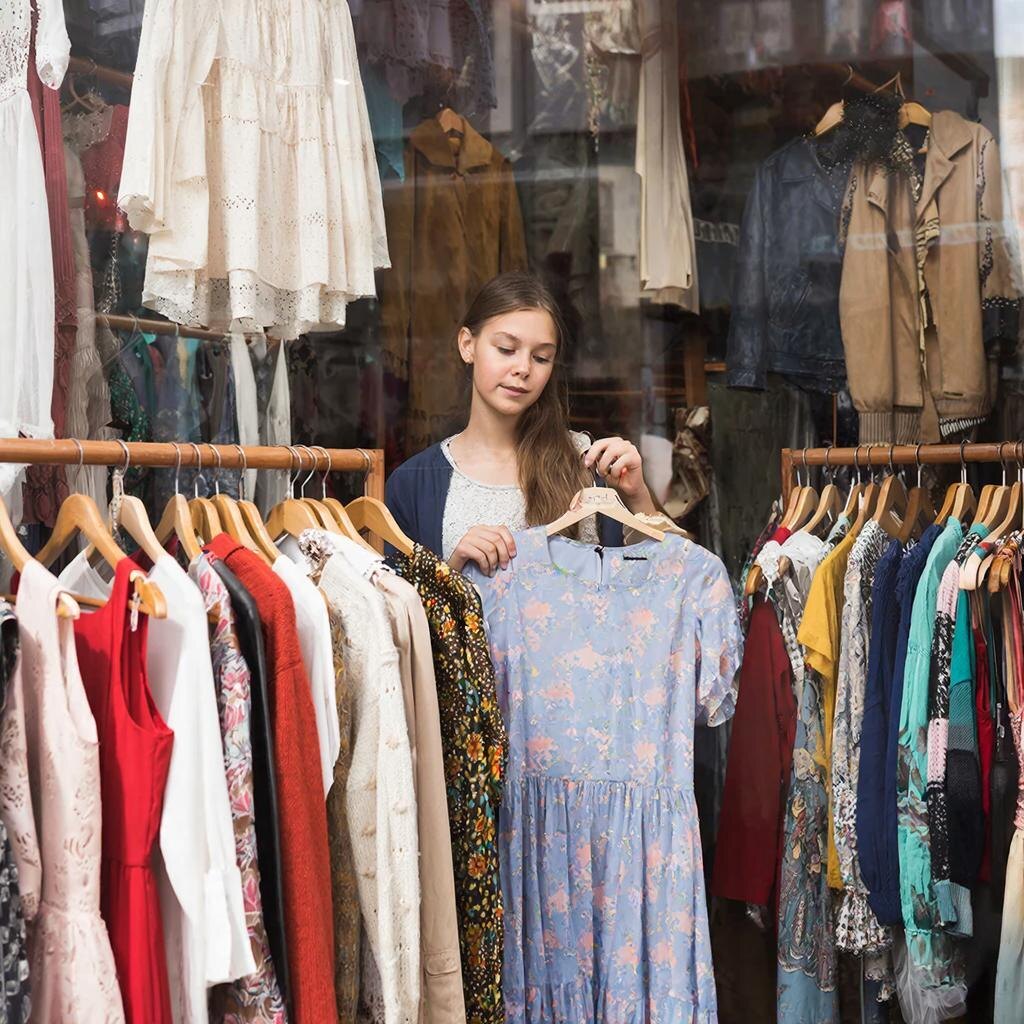 Девушка выбирает платье в секонд-хенде (сгенерированное изображение)