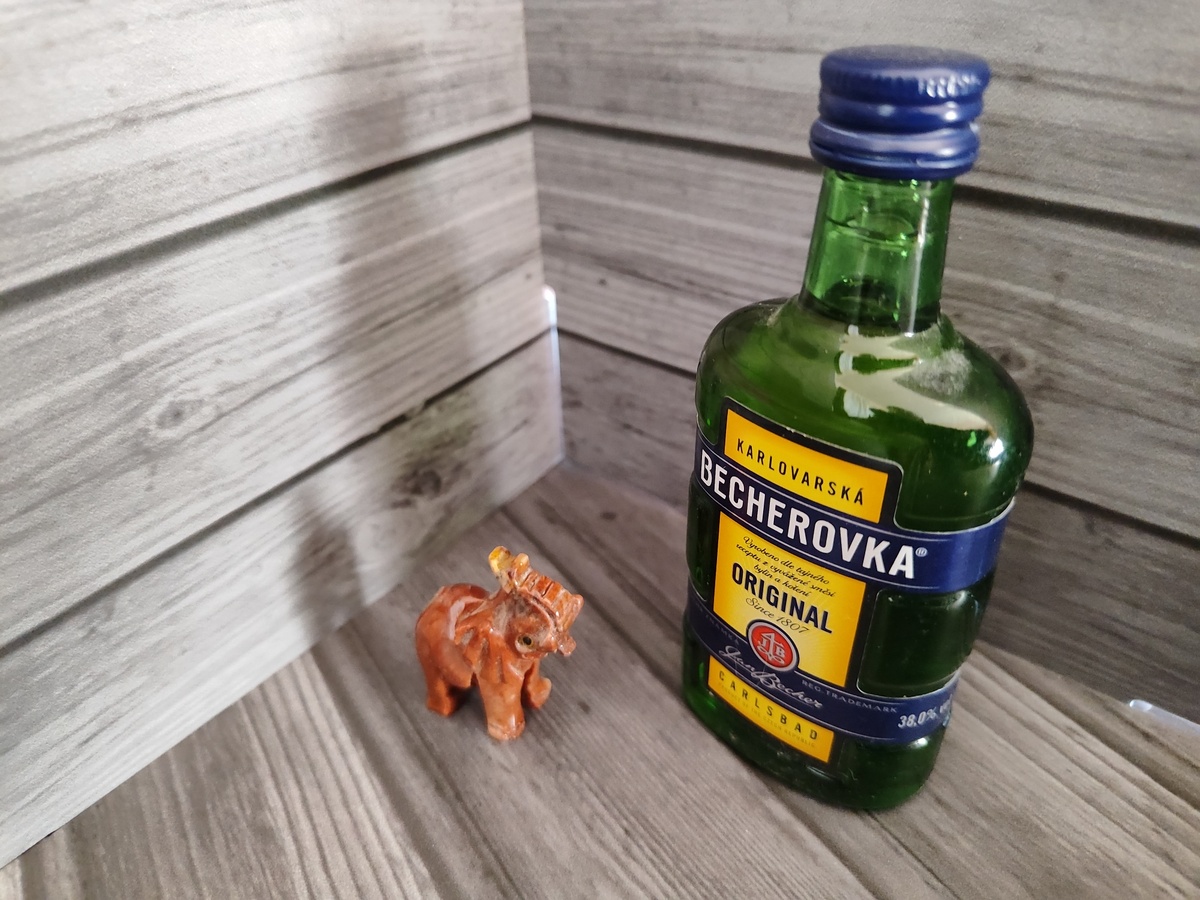 Слоник из Пражского зоопарка мечтательно смотрит на бутылку "Бехеровки" (сувенирную)