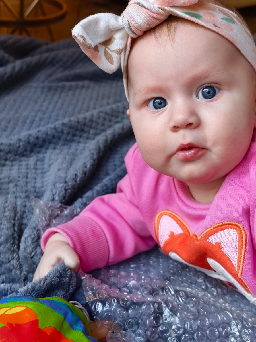 Николь лежит на животе, пока мама ее фотографирует