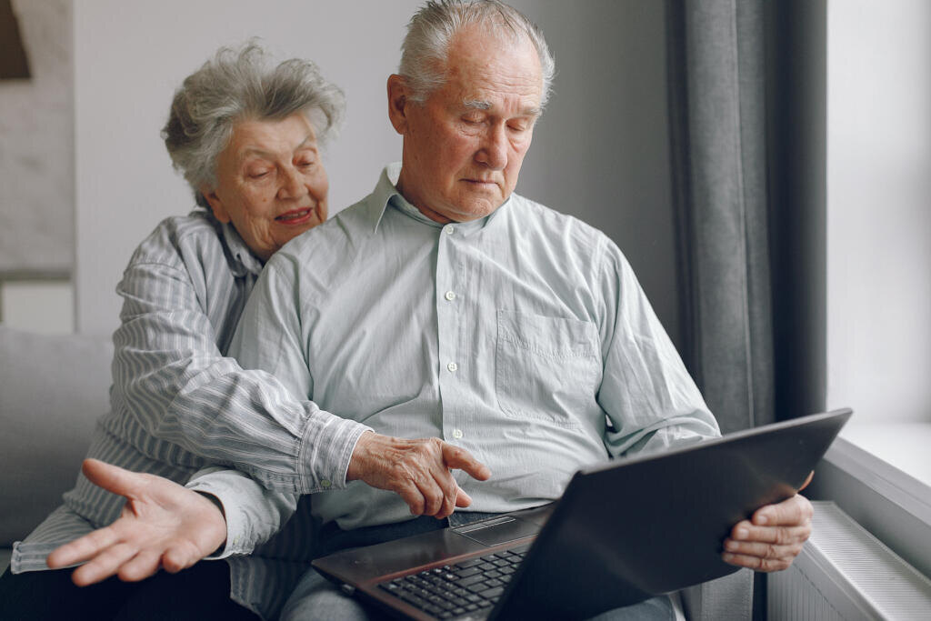    Grandparents at home. Old people use the laptop. Senior in a blue shirt. Журналист