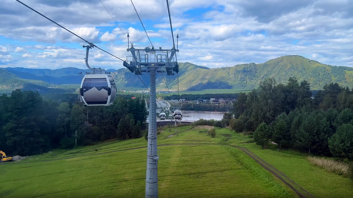 «Взгляд с высоты: подъем на Малую Синюху в кабине канатной дороги Манжерок. За несколько минут вы пролетаете над таежными склонами, а внизу открывается захватывающая панорама на бирюзовое озеро и горы Алтая».