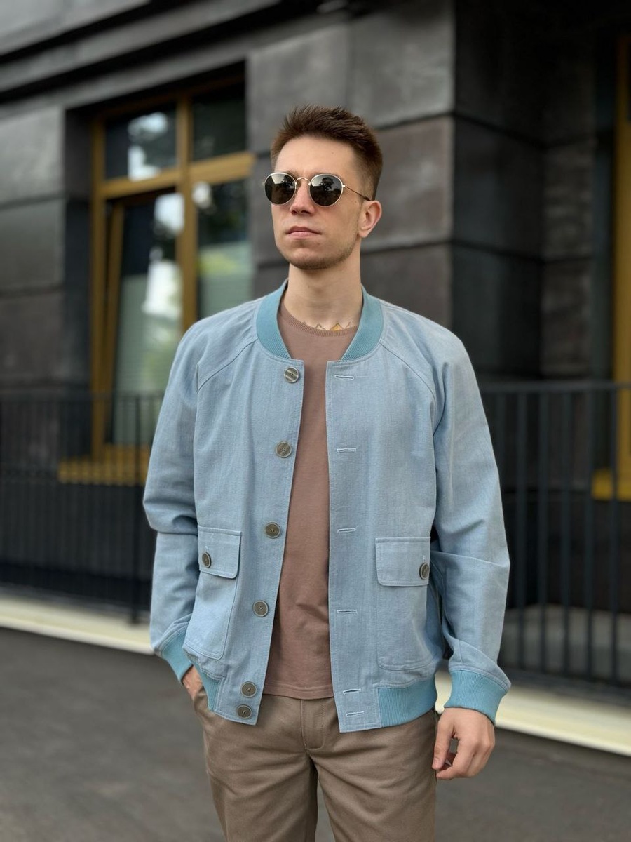 Бомбер без подкладки изготовлен из натуральной ткани серо-голубого цвета с жатым эффектом «крэш». 