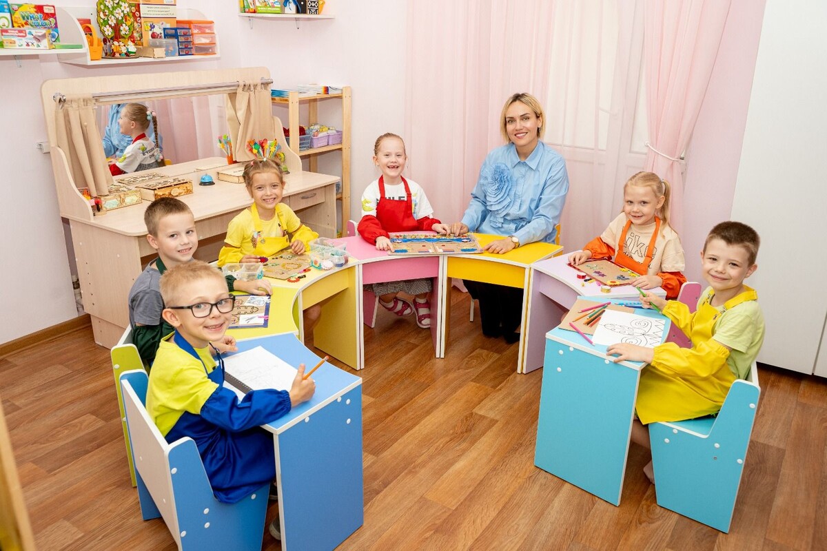 Педагог детского сада за работой с счастливыми детьми