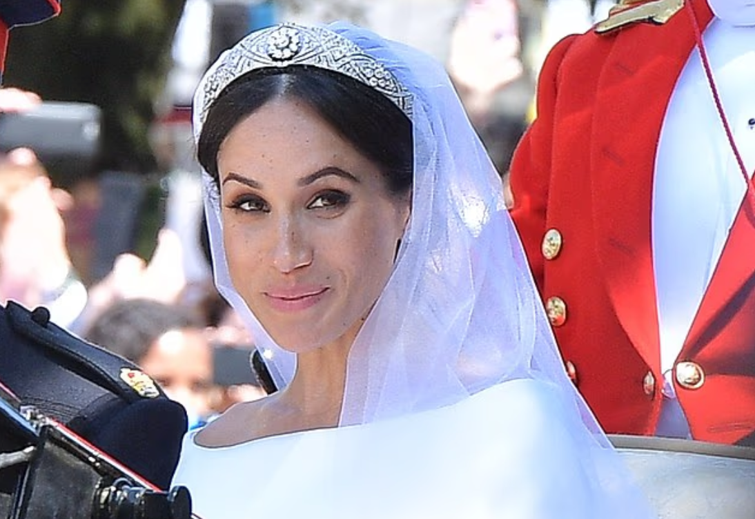 Меган носила бриллиантовую повязку королевы Марии, но одолжение тиары королевой привело к скандалу, когда Сассекские позвонили во дворец и попросили костюмера и куратора королевы Анджелу Келли прислать тиару, потому что Меган хотела попрактиковаться в ее ношении.