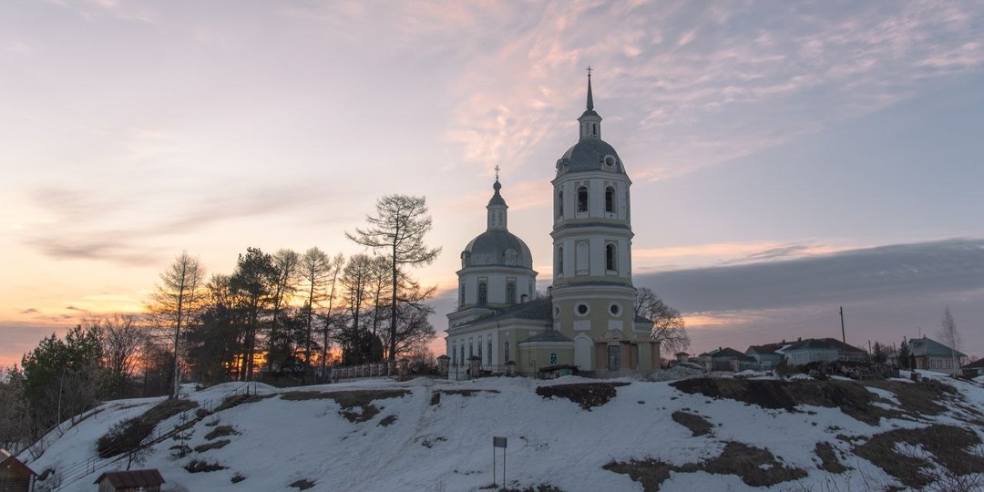 Старинная церковь, укутанная легкой снежной дымкой, на фоне розовеющего неба