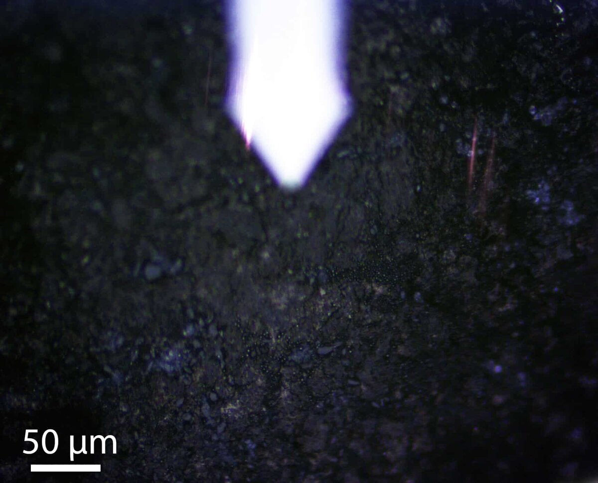    Образец астероида Бенну под оптическим микроскопом в рамках наноразмерного анализа. / © Mehmet Yesiltas