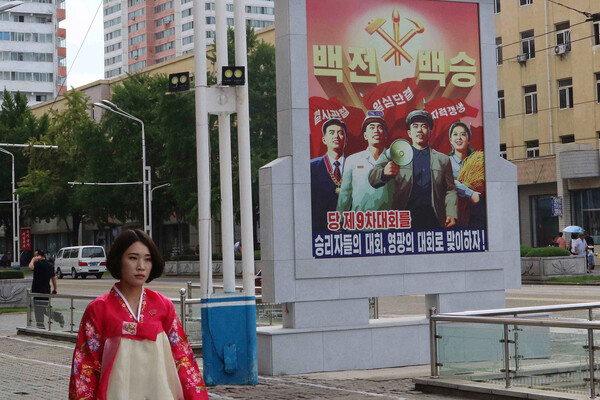 Женщина идет по улице Пхеньяна, на фоне плакат с приветствием IX съезда Трудовой партии Кореи, 2025 год / Jon Chol Jin/AP   📷