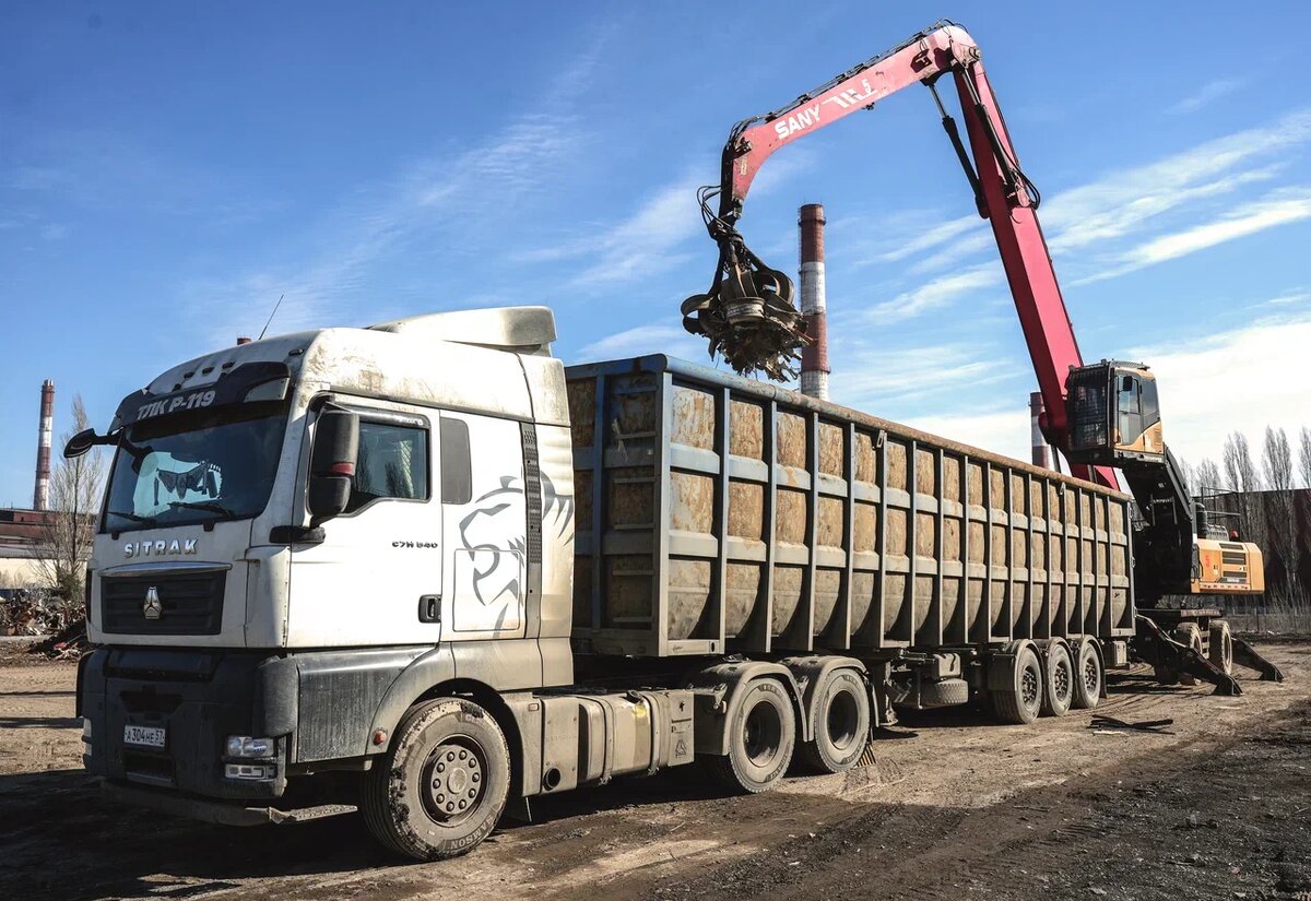 з автомобилей гидроманипулятором-грейфером на открытую площадку выгружают привезённый металлолом. Фото: Александр Белашов / «Медиацентр»