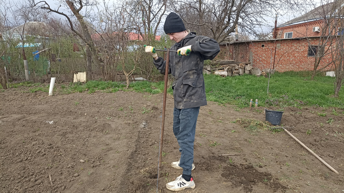 Алексей готовит ямки для заливки столбиков цементной смесью