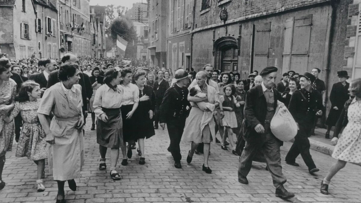 В 1944 году Роберт Капа сфотографировал Симону Тузо, идущую без волос по Шартру с младенцем на руках.
