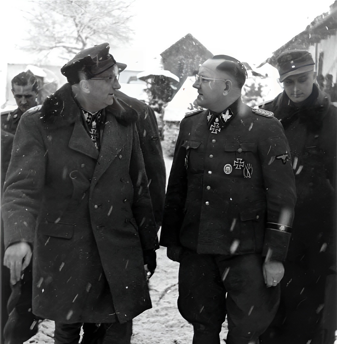 Обергруппенфюрер и генерал-майор Ваффен-СС Герберт Отто Гилле (коммандер-генерал IV танкового корпуса СС) беседует с бригадефюрером и генерал-майором Ваффен-СС Хельмутом Беккером, держа вольховшток (трость для немецких офицеров и унтер-офицеров, типичная для Восточного фронта). (коммандер 3-й танковой дивизии СС «Тотенкопф»), находившийся под его командованием. Крайним слева позади Гилле стоит штурмбаннфюрер СС Адольф Питчеллис (фюрер 3-го танкового полка СС «Тотенкопф»), который позже погиб в бою 26 января 1945 года, всего через несколько дней после того, как была сделана эта фотография!