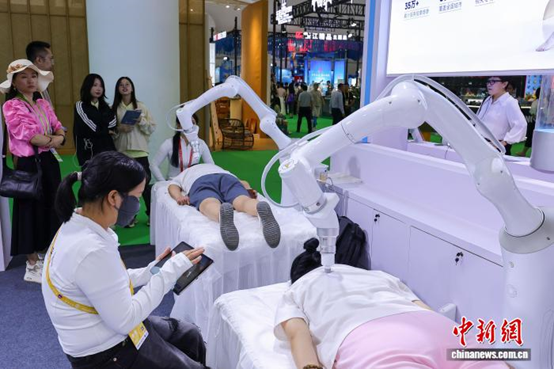 13 апреля в Хайкоу, провинция Хайнань, прошла 6-я Китайская международная выставка потребительских товаров. На фотографии запечатлены посетители, испытывающие на себе массажного робота на выставке. (Фото: Ло Юньфэй, Китайская служба новостей) 4月13日，第六届中国国际消费品博览会在海南海口举办，图为参观者在现场体验一款按摩机器人。　中新社记者 骆云飞 摄
