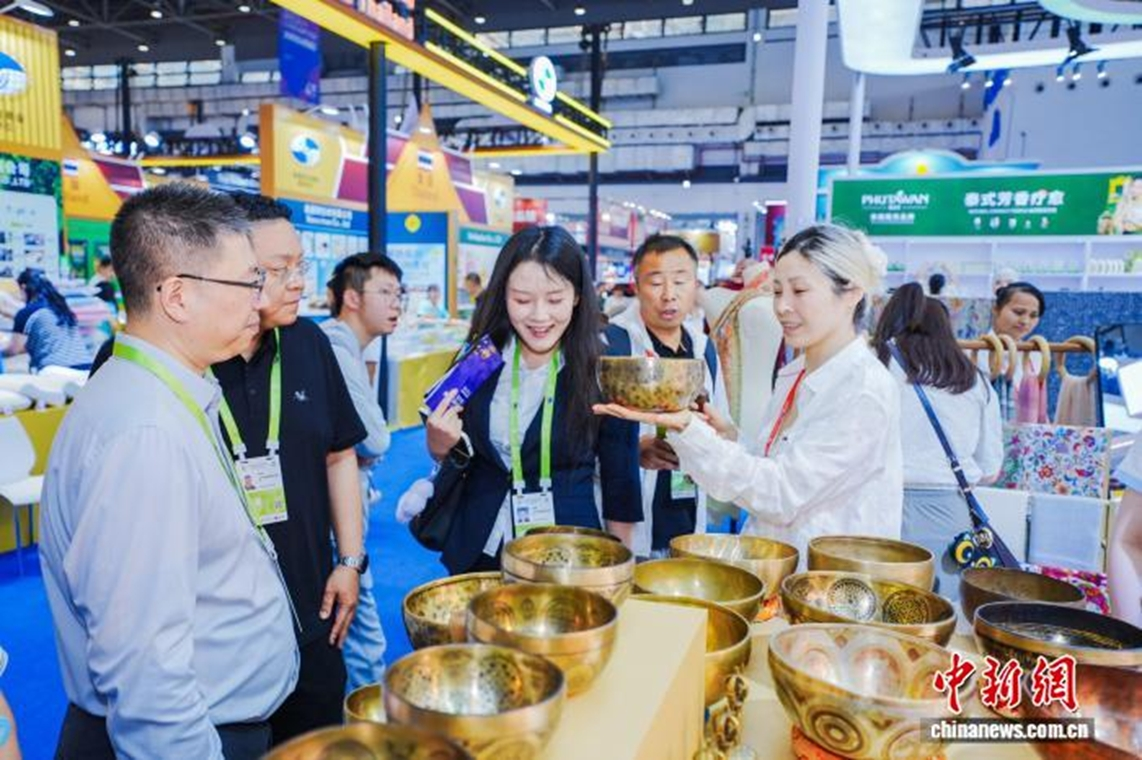 Сотрудники Гренландского глобального павильона, представляющие посетителям зарубежные товары. (Фото Ван Янань) 图为“绿地全球馆”工作人员向观展者介绍外国特色商品。　王亚楠 摄