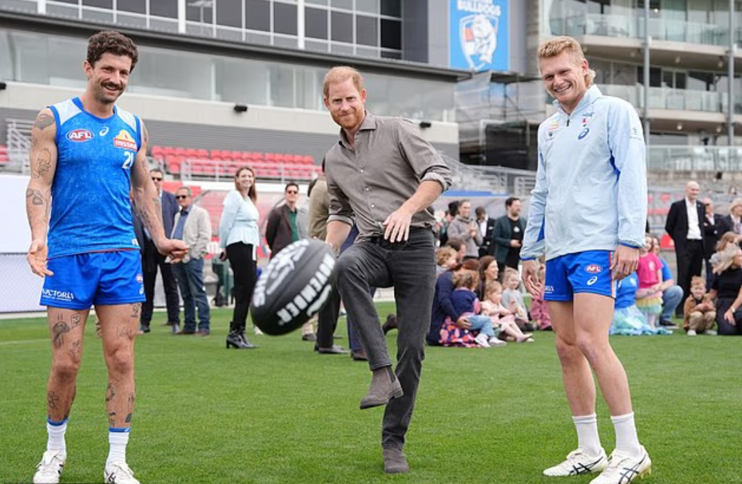 Принц Гарри пинает мяч из шеррина во время футбольной сессии по австралийским правилам Western Bulldogs в Мельбурне сегодня.