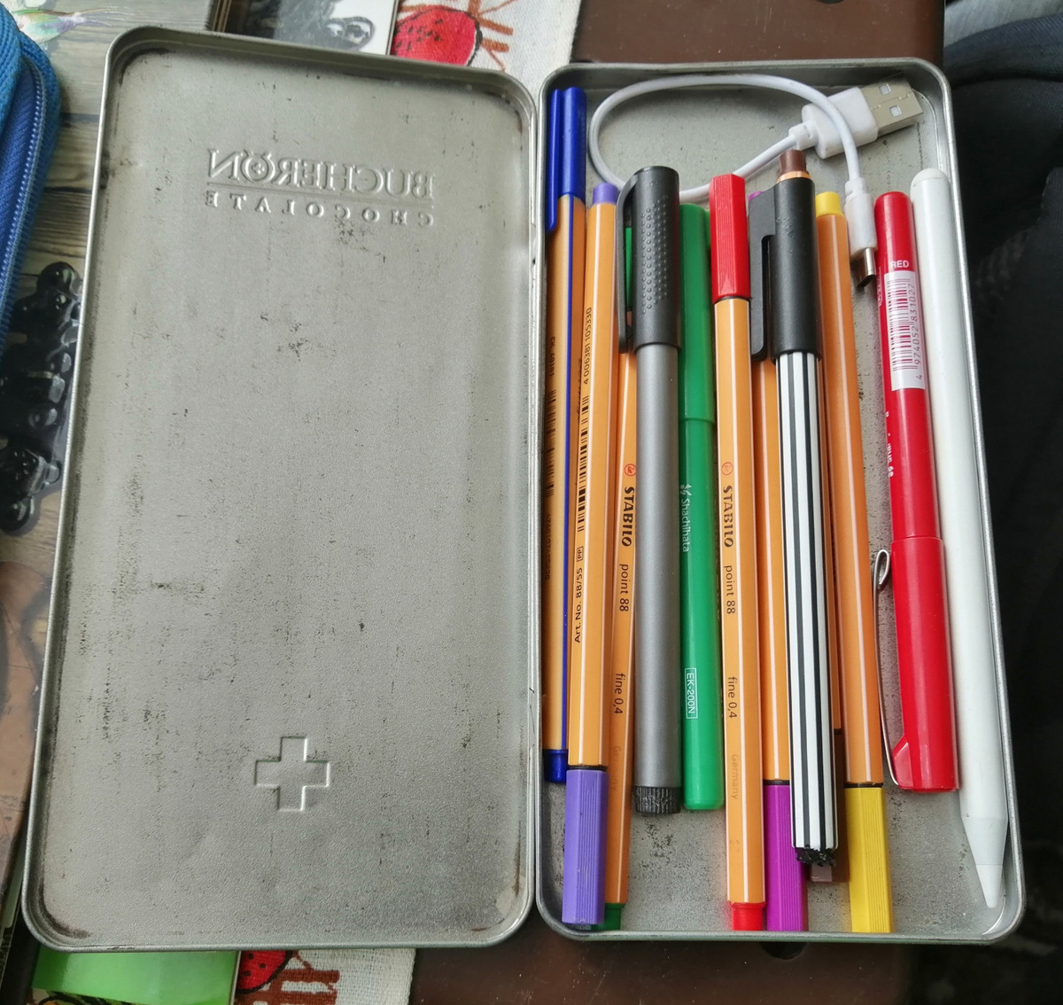 Пенал для линеров. Он слегка переполнен. Но в нём все необходимые цвета, а также стилус для планшета с зарядным кабелем.