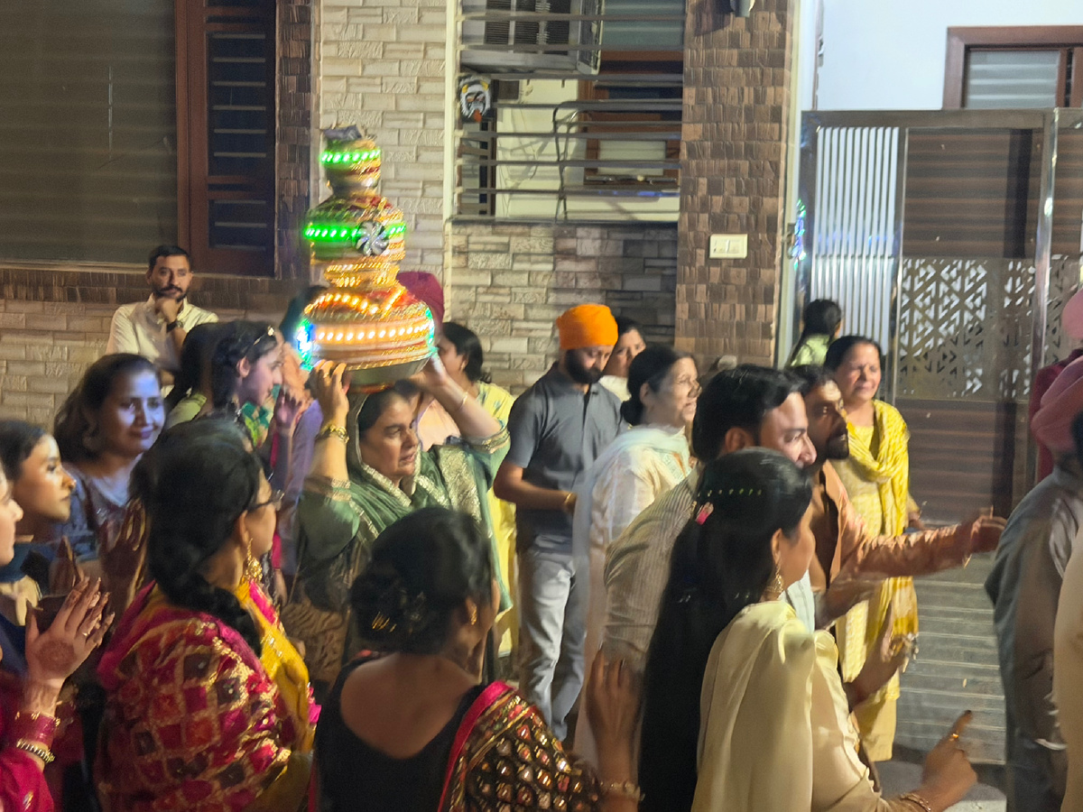 Горшок с LED-гирляндами держат сразу несколько женщин — один человек не справится. Сикх в красном тюрбане наблюдает