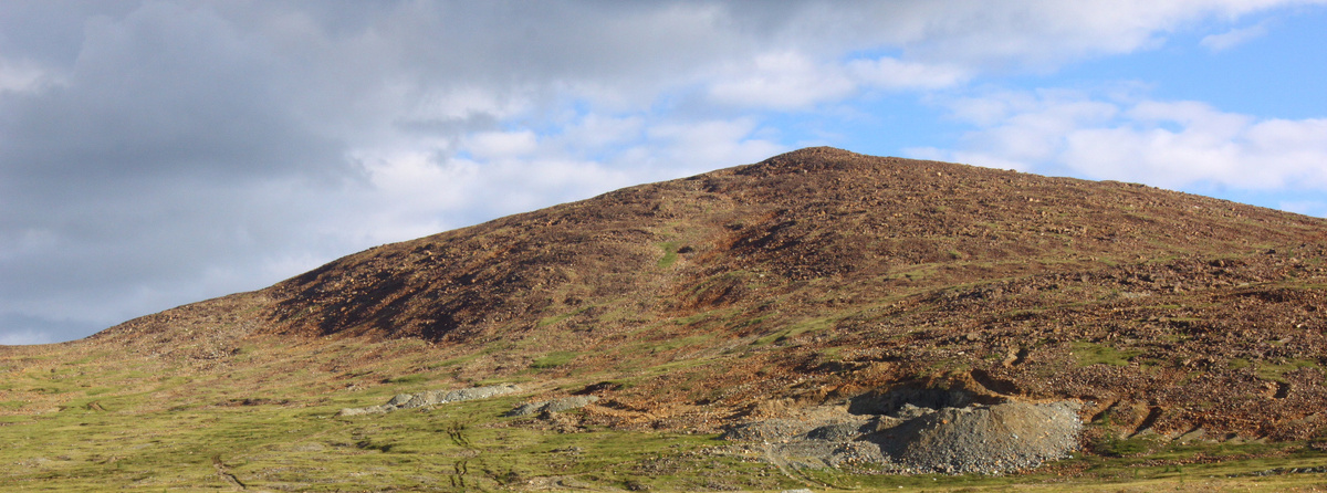 Фото 2. Улан-Ходинское месторождение нефрита. На снимке хорошо видны поверхностные горные выработки и отвалы штольни, вскрывшие жилы нефрита. 
Вид с севера на юг. Июль 2015 г.
