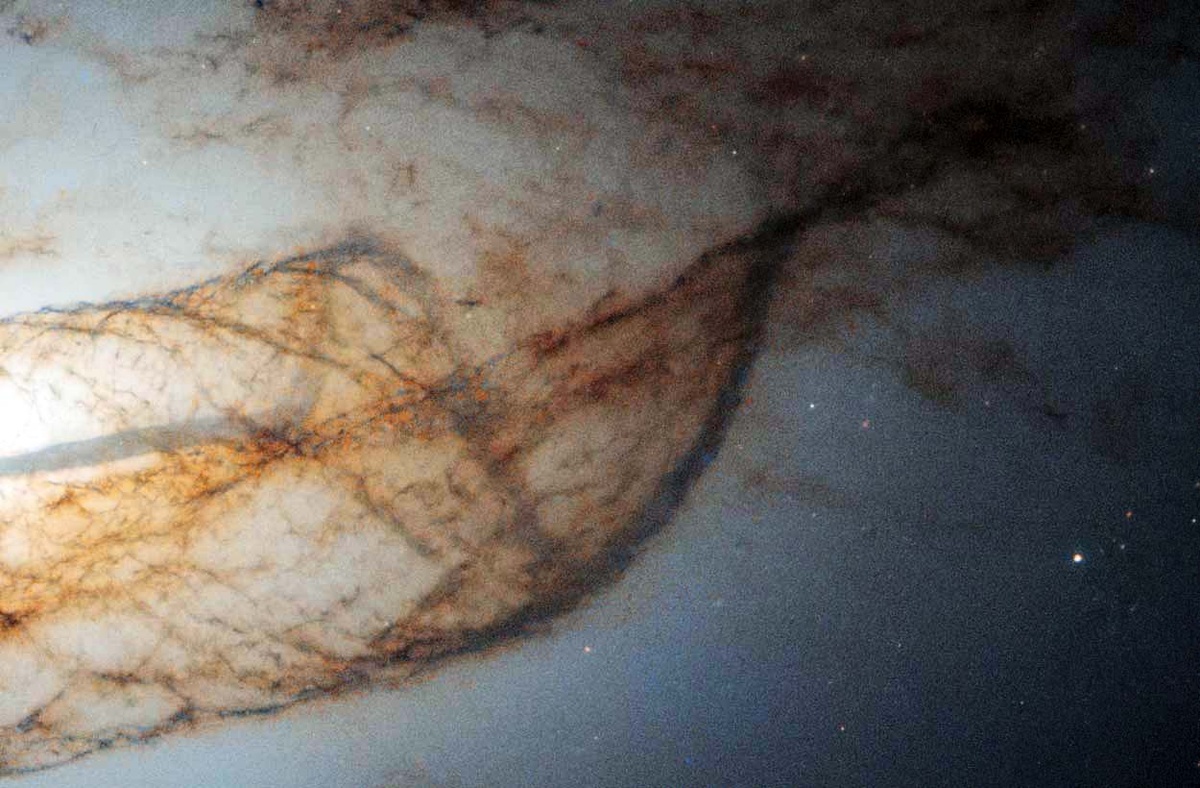 Изображения обработаны для более четкого выделения пылевых полос. Вещество в таких образованиях движется со скоростями в сотни километров в секунду, но на фоне колоссальных размеров галактики эти структуры кажутся неподвижными / © NASA/ESA/TheSpaceway