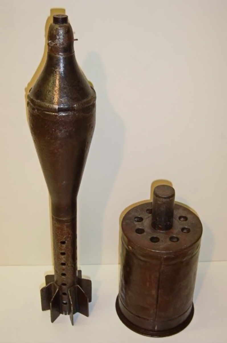 общий вид разобранного выстрела 8 cm Wgr.Patr.4462 (другое обозначение 8 cm W.H1.Gr.Patr.4462). Слева на фото - кумулятивный снаряд (мина) 8 cm Pwk.Gr.5071, а справа – гильза от выстрела. Хорошо видна передняя крышка гильзы, которая имела 8 отверстий (сопел) для выхода газов и шток, который служил для одевания (крепления) на него хвостовой части мины (снаряда).