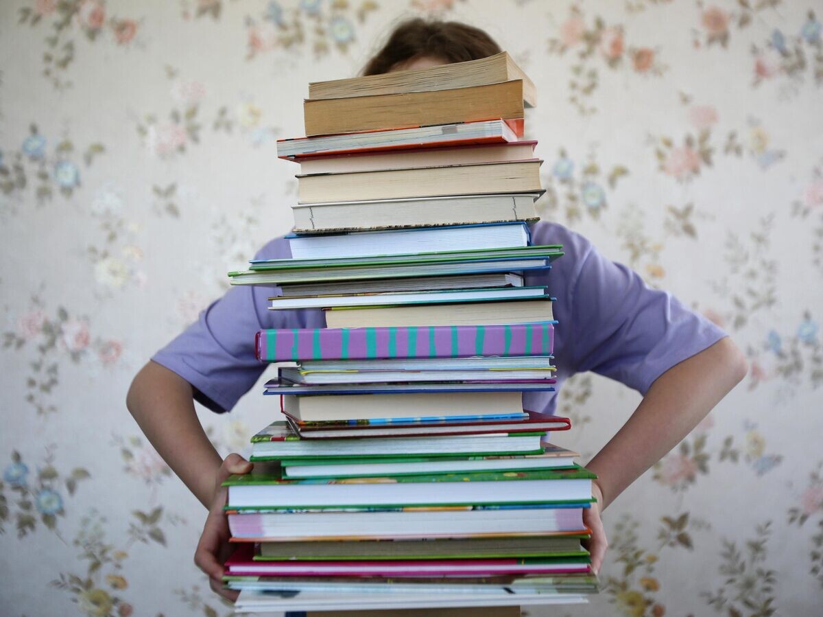    Девочка держит стопку книг | © РИА Новости
