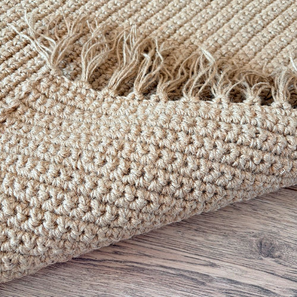 Крупный план джутового ковра RoLens Jute. Видна плотная рельефная фактура плетения, натуральное волокно, природный песочный цвет. Джут — 100% натуральный материал: экологичный, прочный, износостойкий. Не электризуется, не притягивает пыль, легко чистится пылесосом. Подходит для аллергиков и домов с животными.