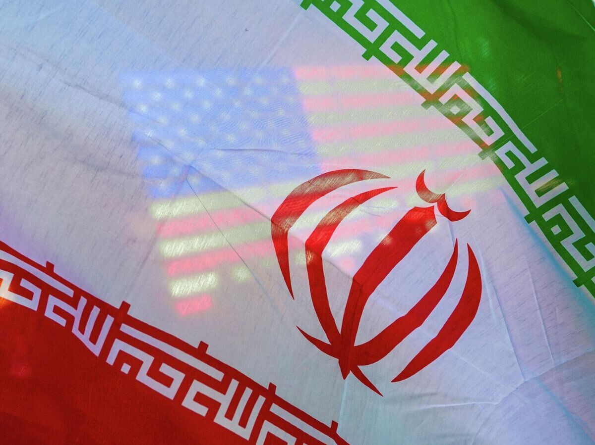    Флаг США виден сквозь флаг Ирана | © AP Photo / Ryan Murphy