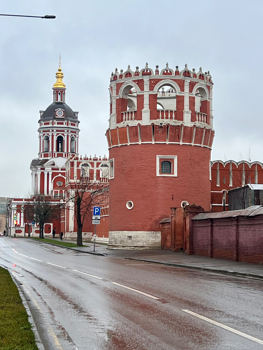  Донской монастырь в Москве — один из старейших монастырей столицы. На переднем плане видна одна из крепостных башен монастыря, выполненная из красного кирпича с характерными белыми декоративными элементами. На заднем плане — надвратная церковь с колокольней, украшенная золотым куполом. Донской монастырь «соседствует» с кладбищем, причём часть кладбища — прямо внутри монастыря, а часть — рядом. 