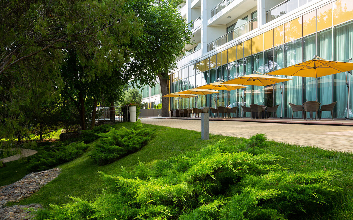 Терраса ресторана и ландшафтный парк в Приморье Grand Resort Hotel 5* на улице Мира, 21. Отель расположен в самом центре Геленджика, на абсолютно ровном участке набережной среди реликтовых сосен. В сезоне 2026 это идеальный выбор для тех, кто ищет премиальный сервис в шаговой доступности от моря без лишних подъемов и лестниц.
